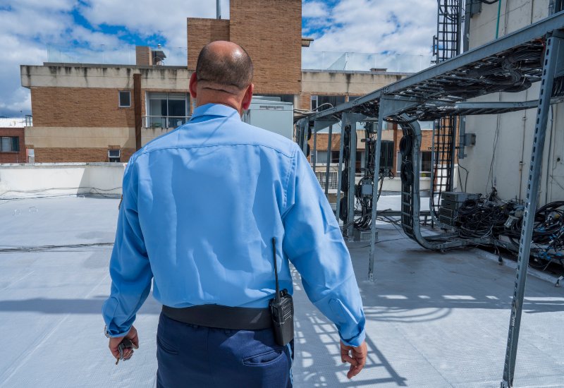 A security guard in a blue shirt walking on a roof at a construction site in San Jose, CA.