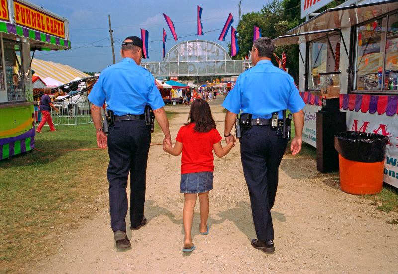 A security officer walks alongside a little girl on a path during the Carnival in San Jose, CA.