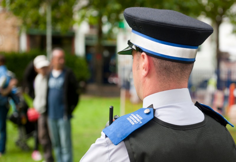 A police officer stands guard in front of a crowd at a funeral in San Jose, CA.