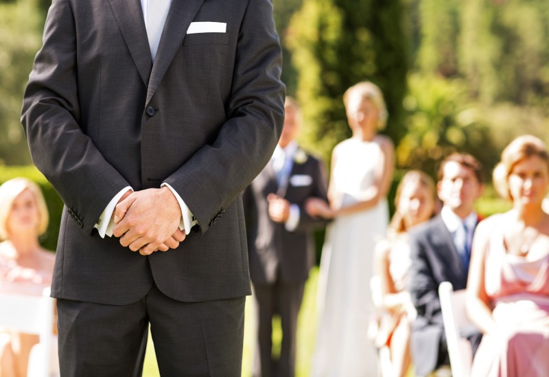 A suited man stands guard in front of a wedding party, ensuring safety at the event in San Jose, CA.